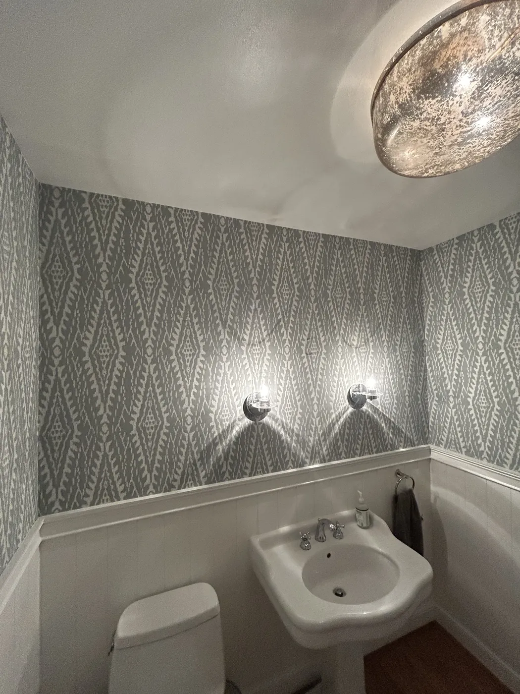 Blue diamond pattern wallpaper above wainscoting in a powder room — wallpaper installation by ProKir Design