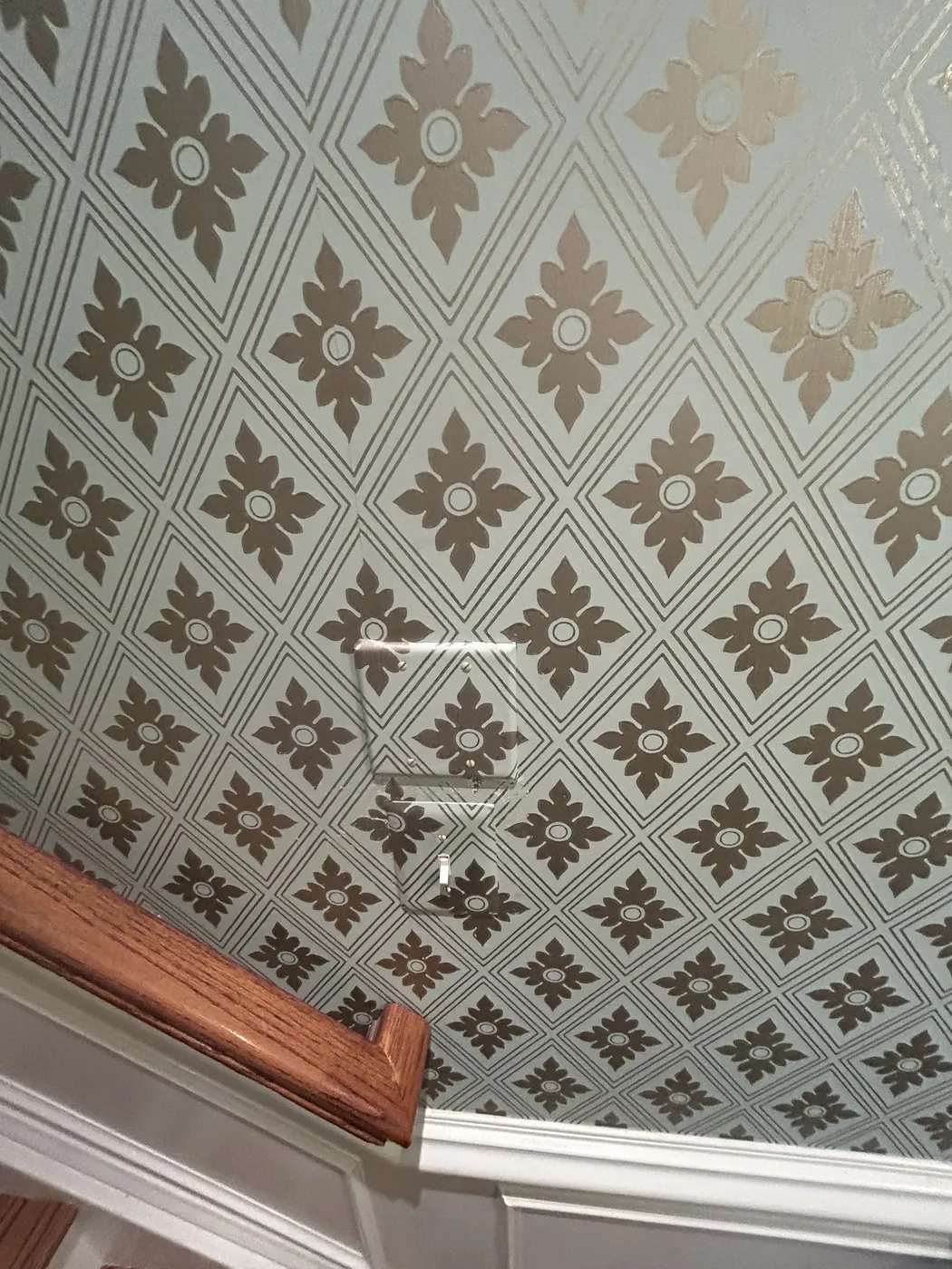 Tan quatrefoil pattern wallpaper over a stair landing — wallpaper installation by ProKir Design