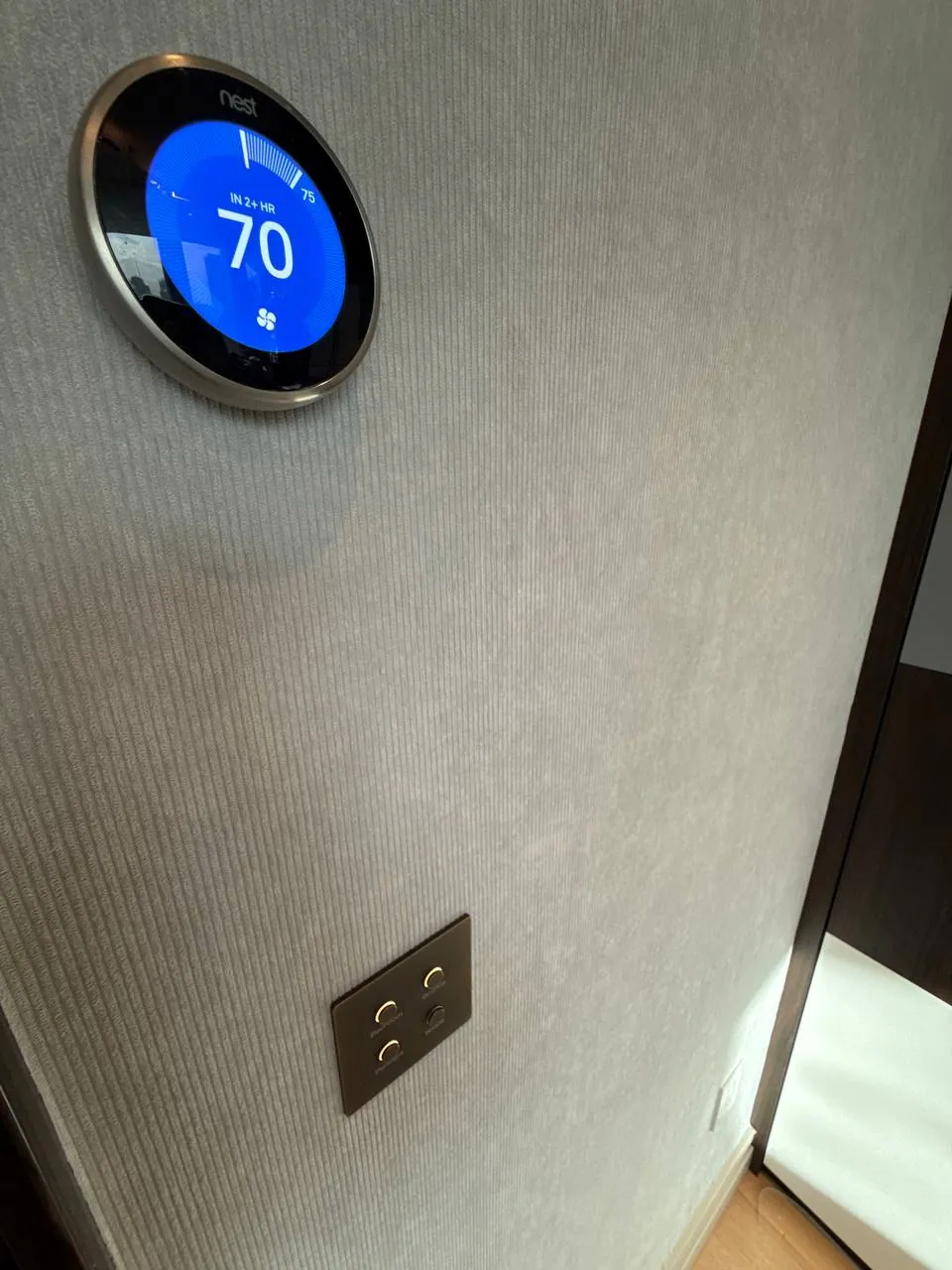 Grasscloth trimmed neatly around a thermostat and switch — wallpaper installation by ProKir Design