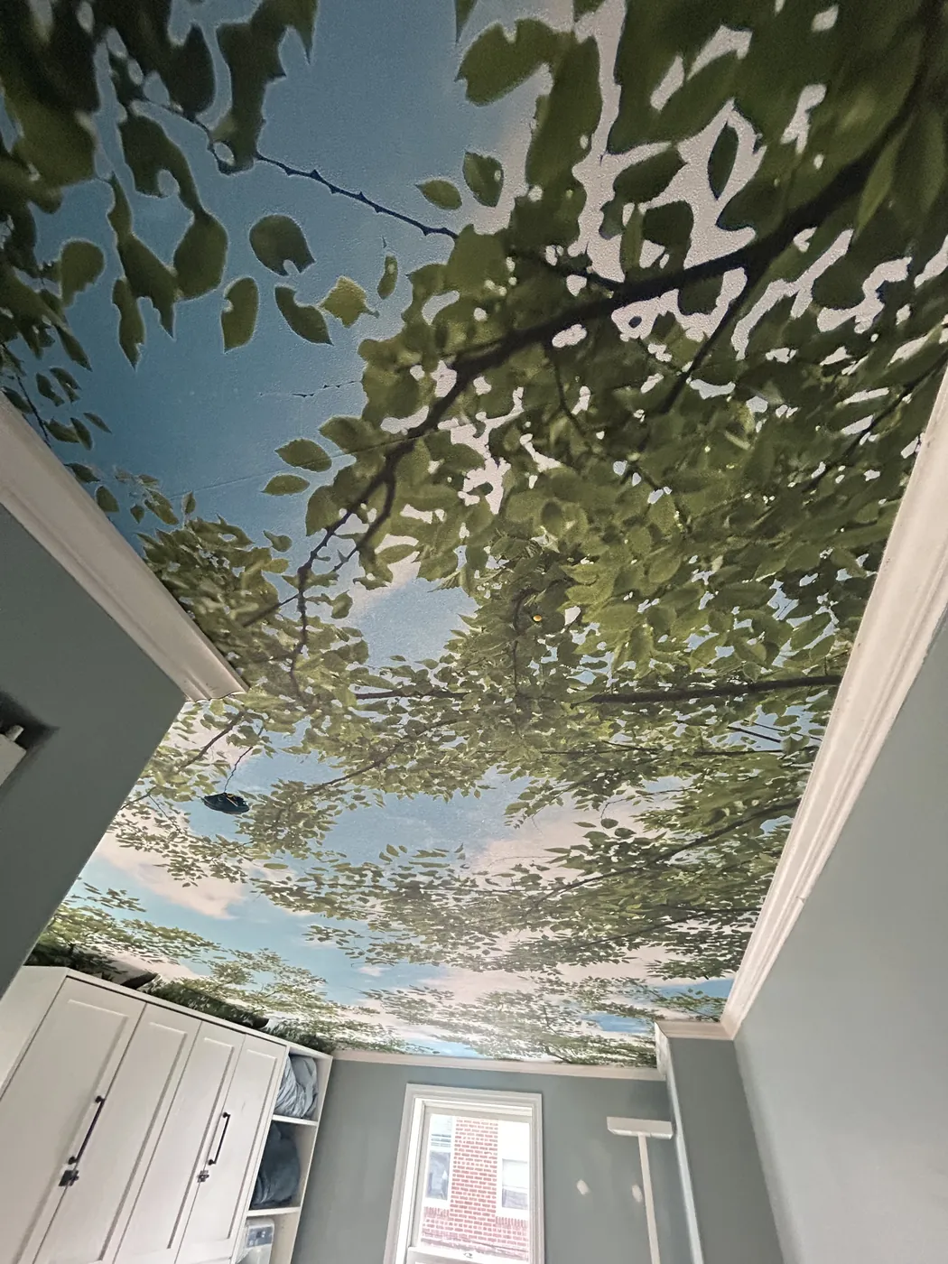 Blue sky and tree canopy mural installed on a ceiling — wallpaper installation by ProKir Design