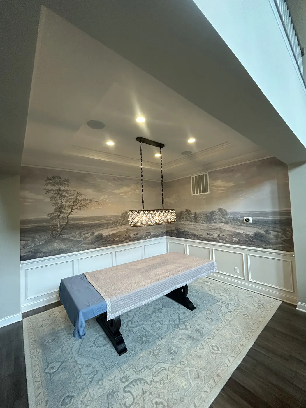 Panoramic landscape mural above white wainscoting in a dining room — wallpaper installation by ProKir Design